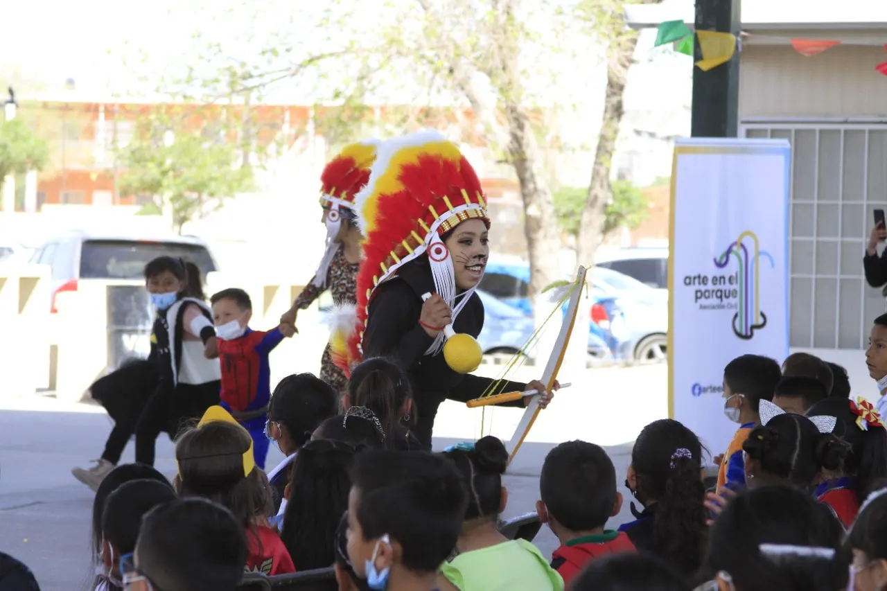 Niñas y niños observan a un danzante con penacho en una actividad comunitaria